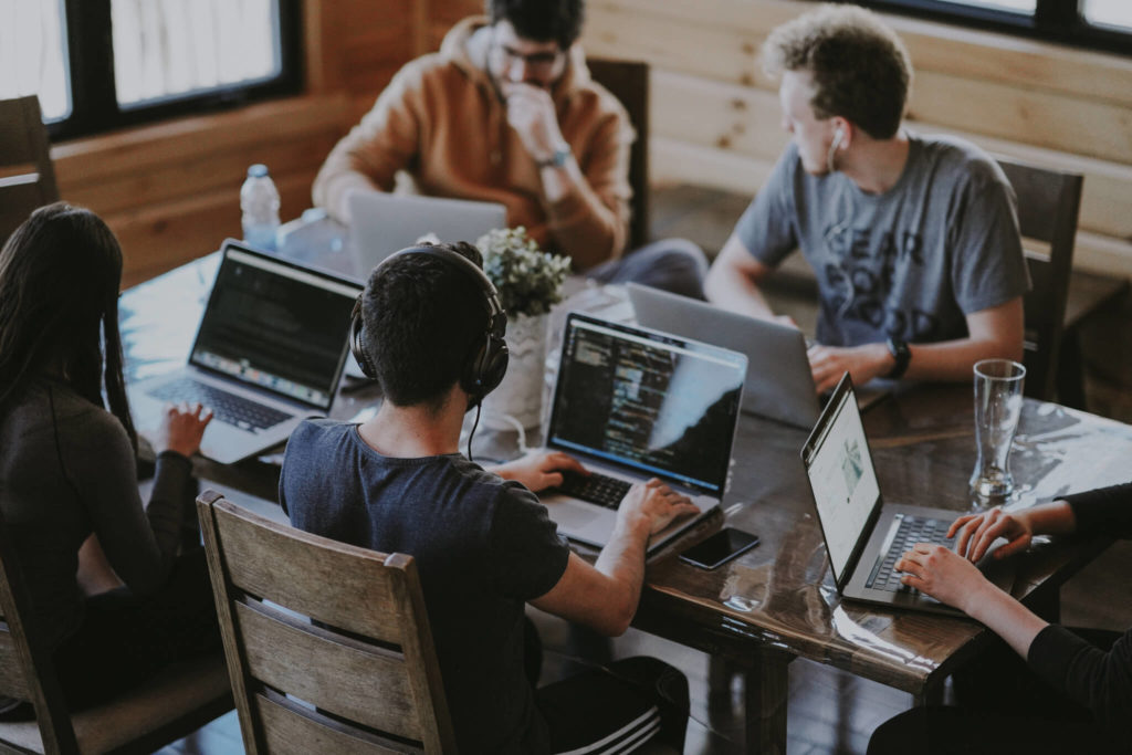 Group of people working at laptops at a desk
